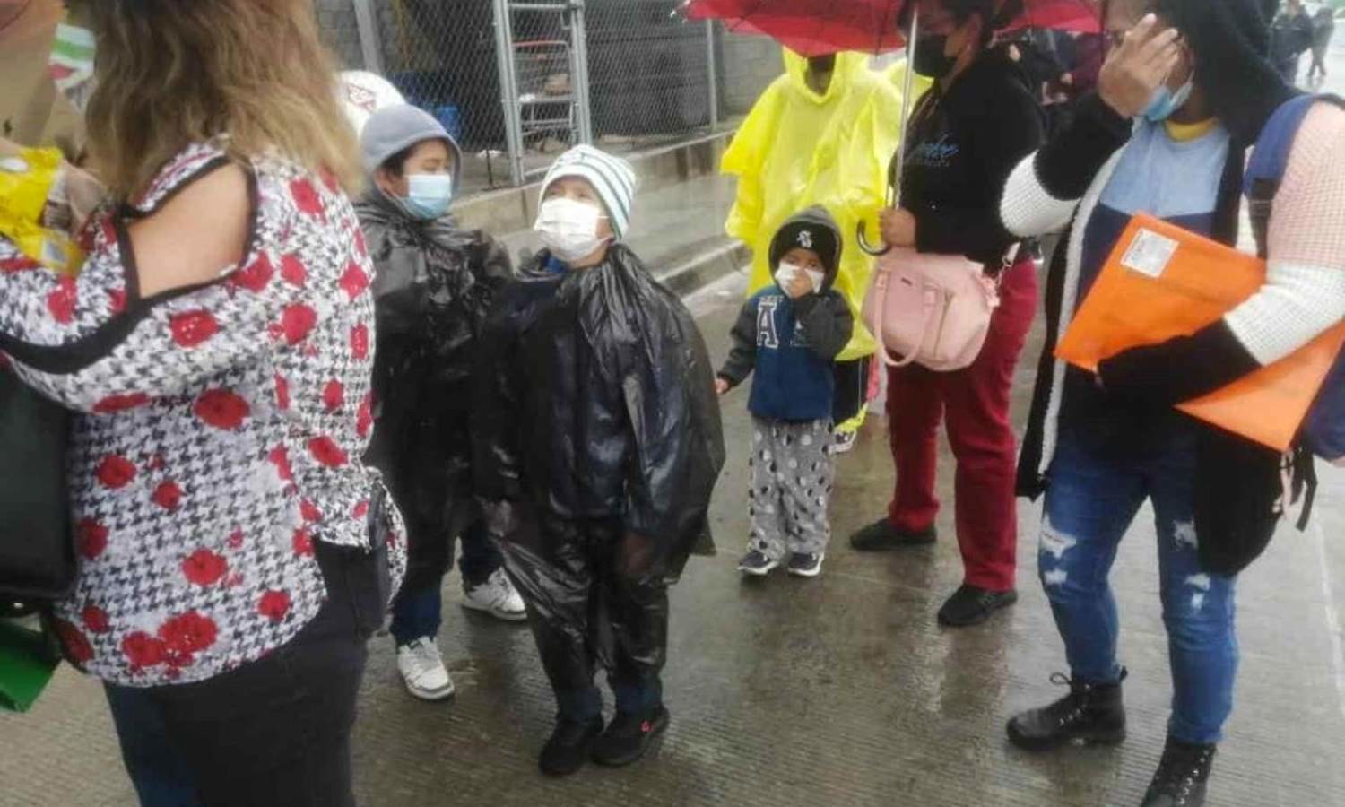 Niños esperan bajo la lluvia para vacunarse contra Covid-19
