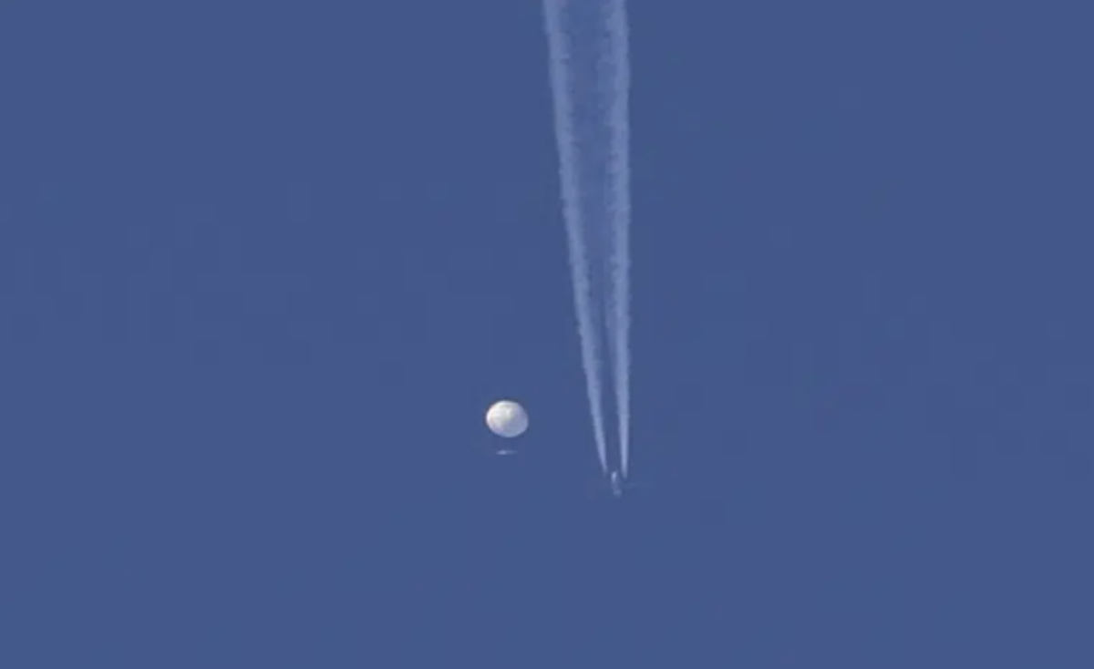 Un gran globo se desplaza por encima de la zona de Kingstown, Carolina del Norte, mientras por debajo se observa un avión y la estela que deja a su paso. (Brian Branch vía AP)