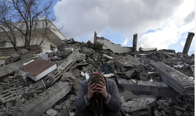 Una mujer sentada sobre los escombros de un edificio que se derrumbó por el sismo del lunes en Nurdagi, sur de Turquía.  (AP Foto/Khalil Hamra)