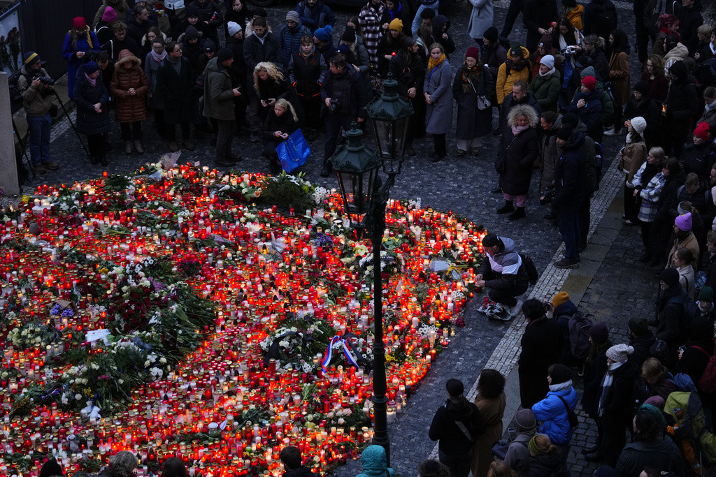 Dolientes llevan flores y velas afuera del edificio de la Facultad de Filosofía de la Universidad Charles en Praga, República Checa, el viernes 22 de diciembre de 2023, un día después de un tiroteo que dejó más de una decena de muertos. (AP Foto/Petr David