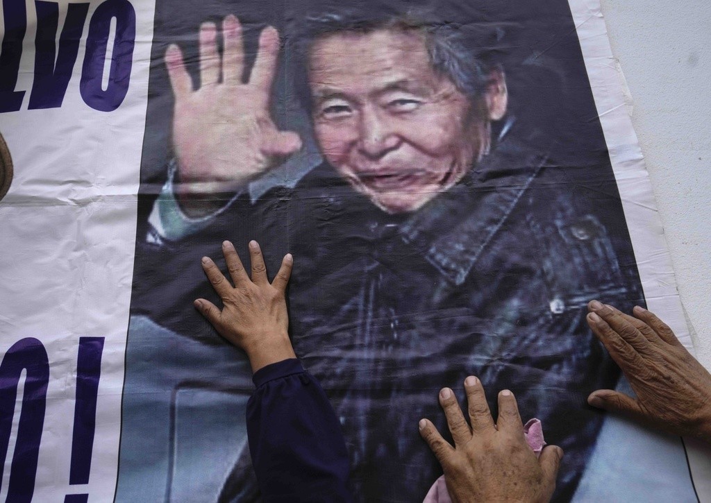 Los partidarios del expresidente encarcelado Alberto Fujimori tocan un cartel con su foto, afuera de la prisión donde está internado en las afueras de Lima, Perú, el martes 5 de diciembre de 2023. (AP Foto/Martín Mejía)