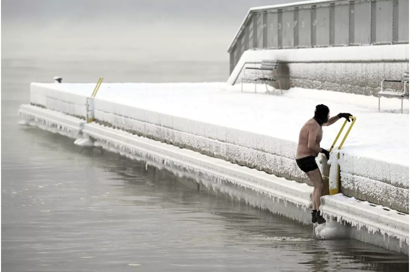 Un hombre sale del mar helado hasta el muelle, en el sur de Helsinki, Finlandia, el martes 2 de enero de 2024. Cuando las temperaturas cayeron a más de -40 grados. (Vesa Moilanen / Associated Press)