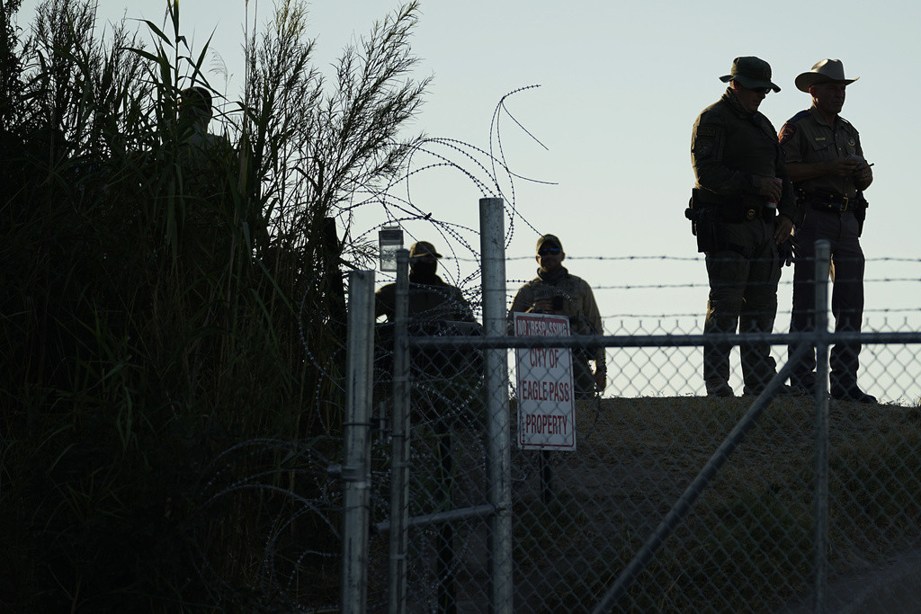 Policías estatales de Texas vigilan junto a un letrero de 'Prohibido el paso' y alambre de púas a lo largo de las márgenes del río Bravo (o Grande), el 1 de agosto de 2023, en Shelby Park, Eagle Pass, Texas. (AP Foto/Eric Gay, Archivo)