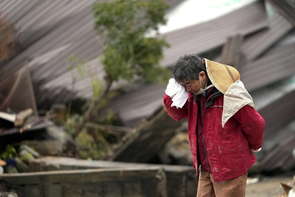 Un hombre llora mientras encuentran los restos de un familiar entre los restos de una vivienda que se vino abajo por un potente sismo en Suzu, en la prefectura de Ishikawa, Japón, el 3 de enero de 2024. (AP Foto/Hiro Komae)