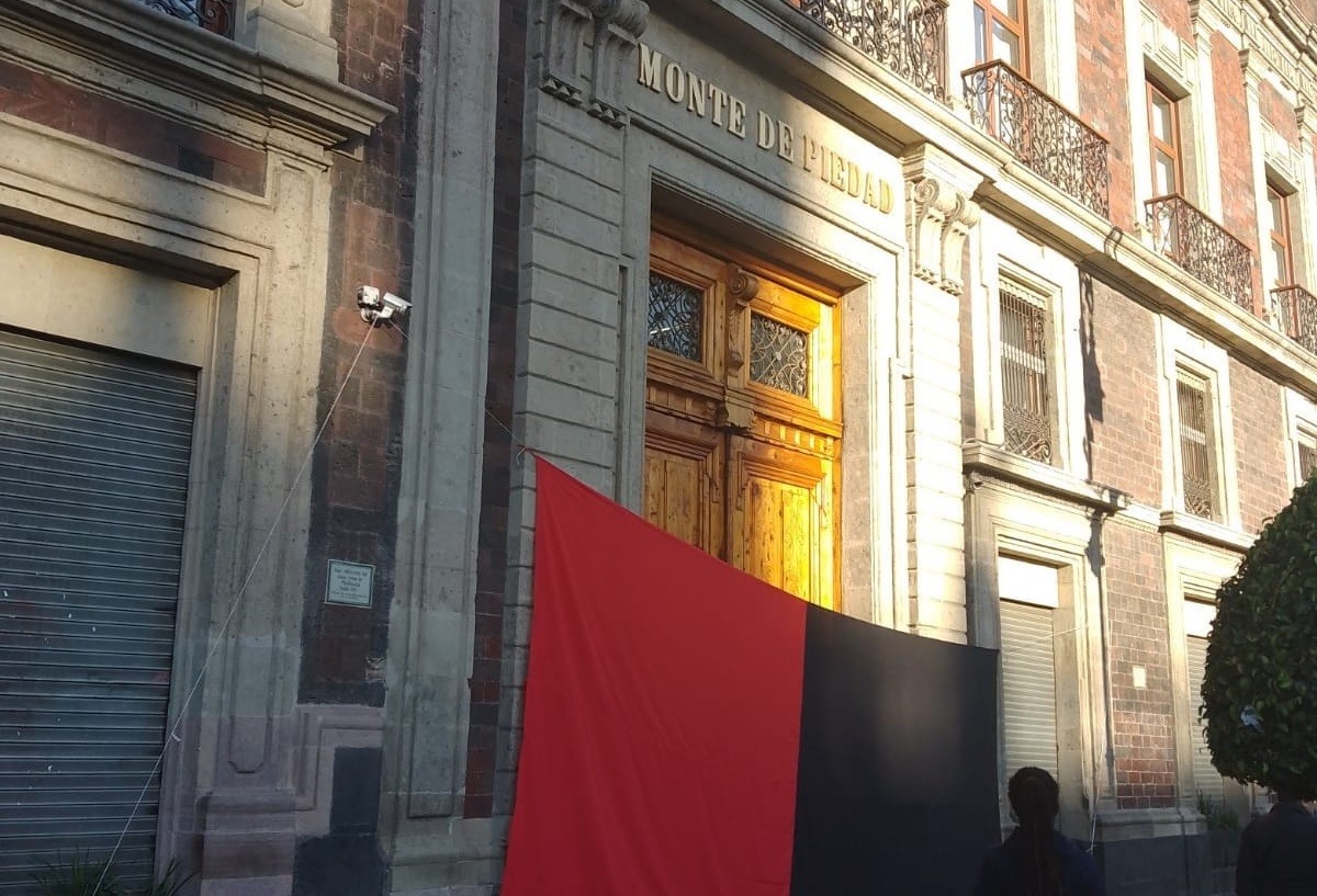 Una bandera rojinegra cuelga de la puerta principal de una sucursal del Nacional Monte de Piedad de la CDMX Foto: Twitter @vialhermes