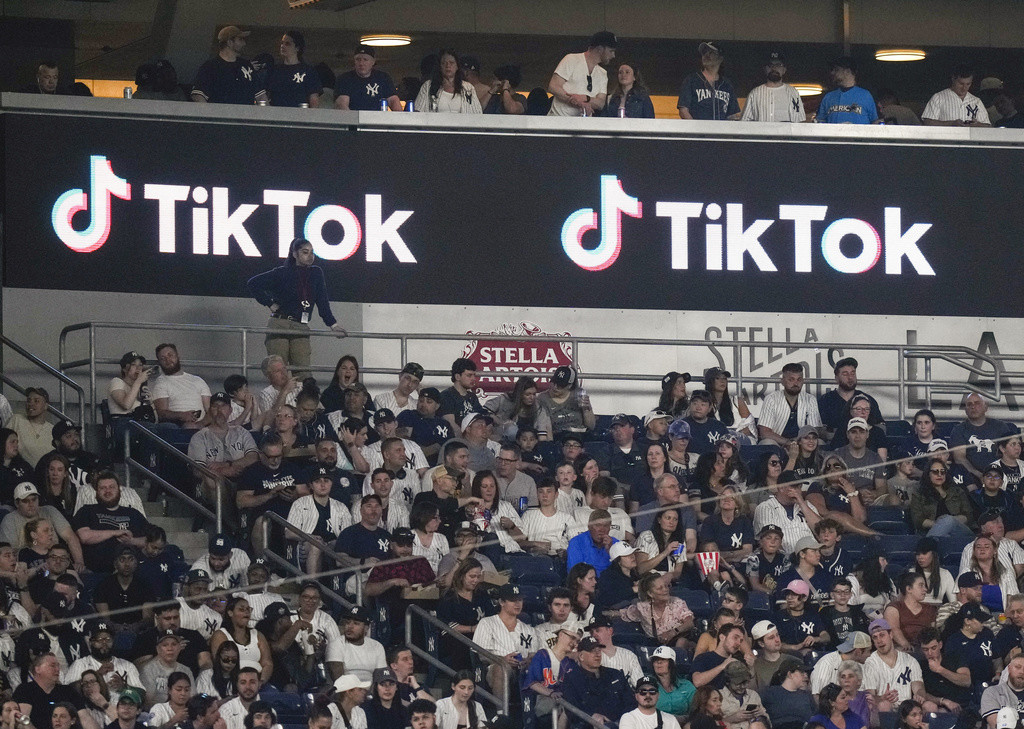 Aficionados están sentados bajo un anuncio de TikTok mientras asisten a un partido de béisbol en el Yankee Stadium, el 14 de abril de 2023, en Nueva York. (AP Foto/Frank Franklin II, Archivo)