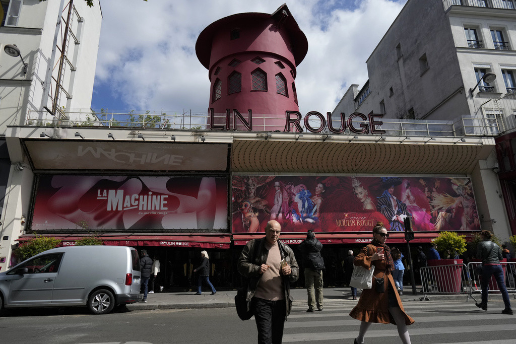 Gente pasa frente al Moulin Rouge, París, jueves 25 de abril de 2024. Las aspas de molino del cabaret parisino del siglo XIX cayeron durante la noche junto con algunas letras del nombre. No se informó de heridos. (AP Foto/Thibault Camus)