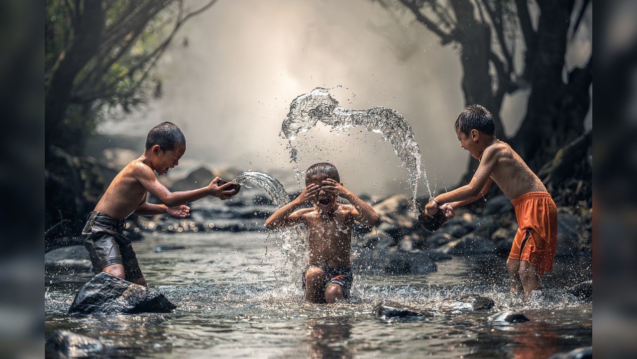 Tres niños disfrutando de un baño sobre un río. Foto: Pixabay.