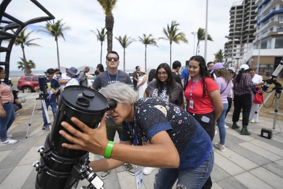 Una astrónoma aficionada prepara su telescopio el día antes de un eclipse solar en Mazatlán.(AP Foto/Fernando Llano)