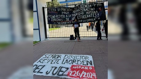 Estudiante protesta encadenado afuera de la ByCENED. Denuncia injusticias