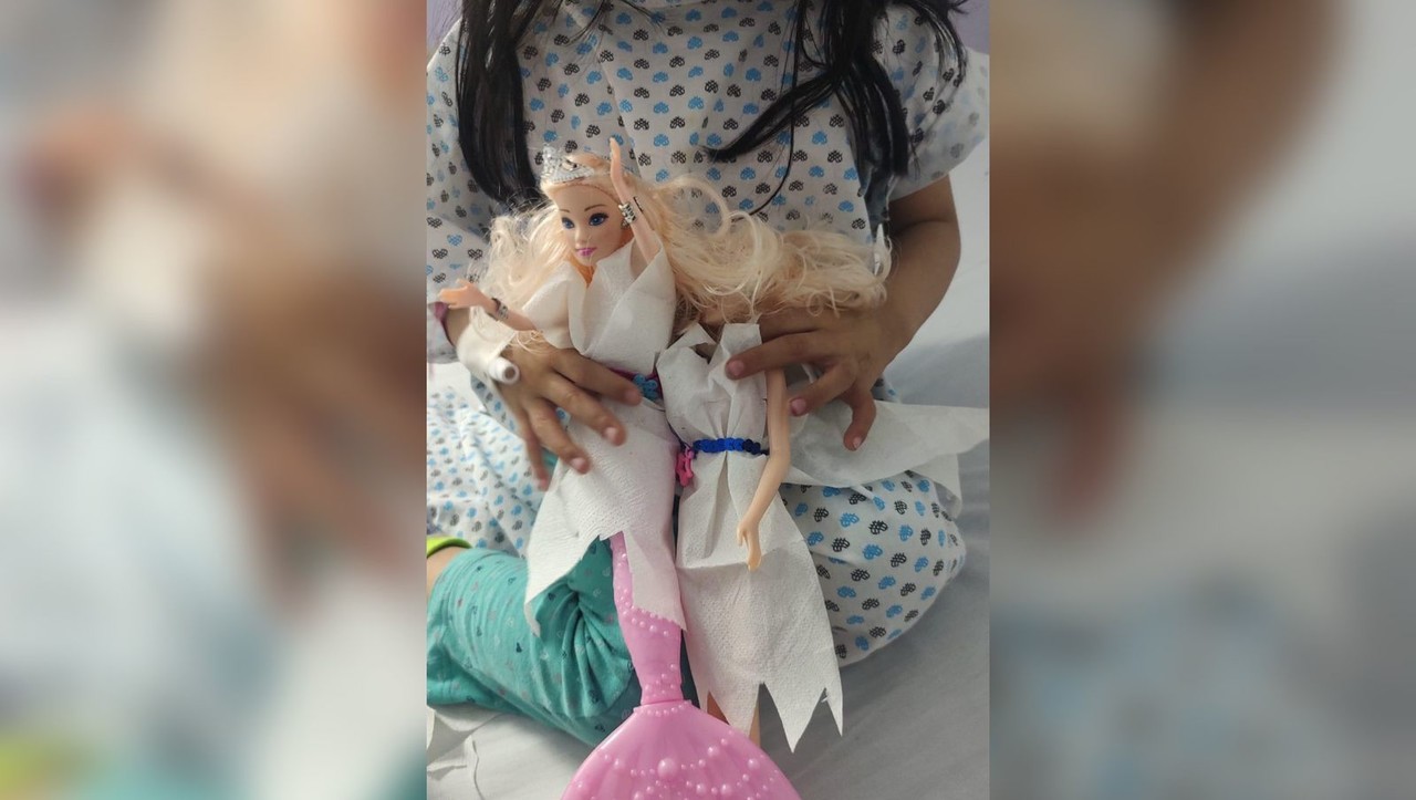 La niña Camila sosteniendo dos Barbies a las que confeccionó ropa hecha con papel higiénico. Foto: Facebook Daniela Chairez.
