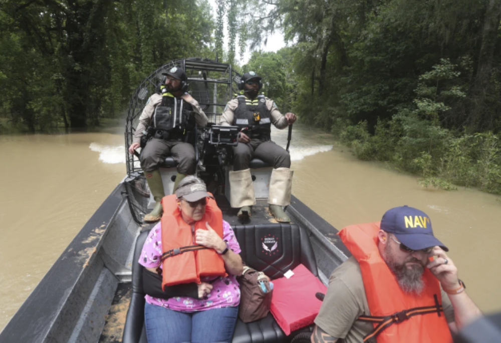 Guardias del Departamento de Parques y Vida Silvestre de Texas, utilizan un bote para rescatar a residentes de las inundaciones en el condado Liberty, Texas,. (AP Foto/Lekan Oyekanmi)