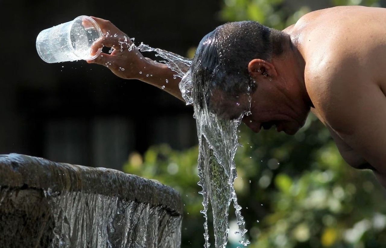 Una persona echandose agua encima de su cabeza para refrescarse por el calor en México. Foto: El País.