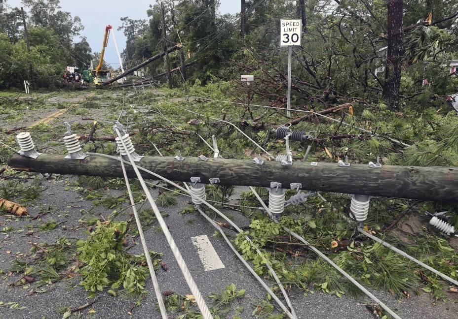 Cuadrillas de trabajadores retiran postes quebrados y cableado eléctrico derribado por los fuertes vientos, en una calle de Tallahassee, Florida, el viernes 10 de mayo de 2024. (AP Foto/Phil Sears)