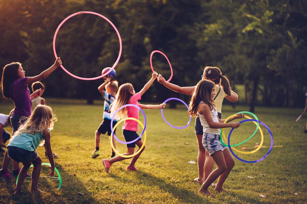 Niños jugando en el pasto con aros. Foto: Canva