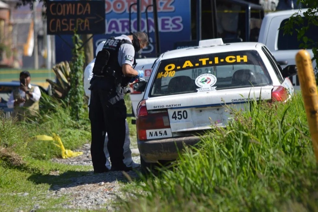 Un elemento de la Fiscalía General de Justicia de Guerrero llevando a cabo una diligencia en el taxi abandonado. Foto: El Sol de Chilpancingo.