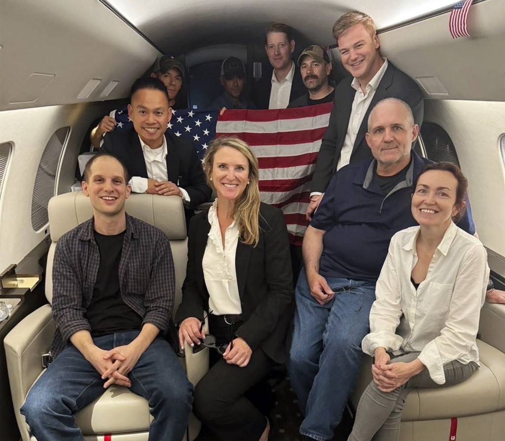 Evan Gershkovich, izquierda, Alsu Kurmasheva, derecha, y Paul Whelan, segundo de la derecha, junto con otras personas a bordo de un avión el 1 de agosto de 2024 tras un intercambio de prisioneros con Rusia. (Casa Blanca vía AP)