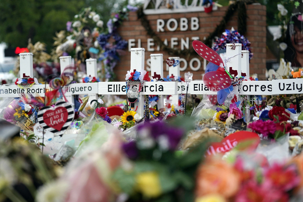 Cruces con flores y otros artículos yacen en un monumento en honor de las víctimas de un tiroteo en la Escuela Primaria Robb, el 9 de junio de 2022, en Uvalde, Texas. (AP Foto/Eric Gay, archivo)