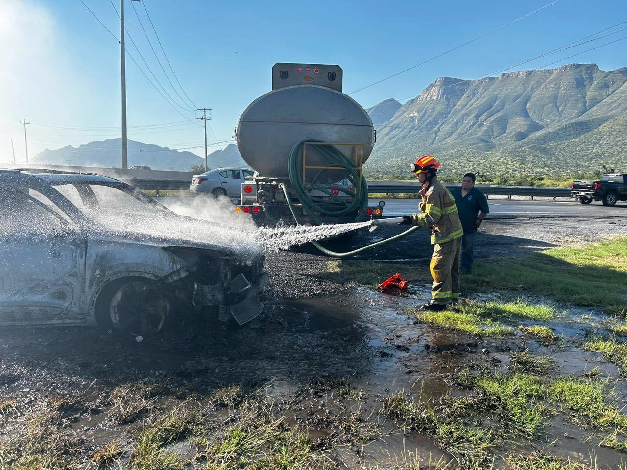 Bombero de Protección Civil sofocando el incendio del auto. Foto: Protección Civil de Nuevo León.