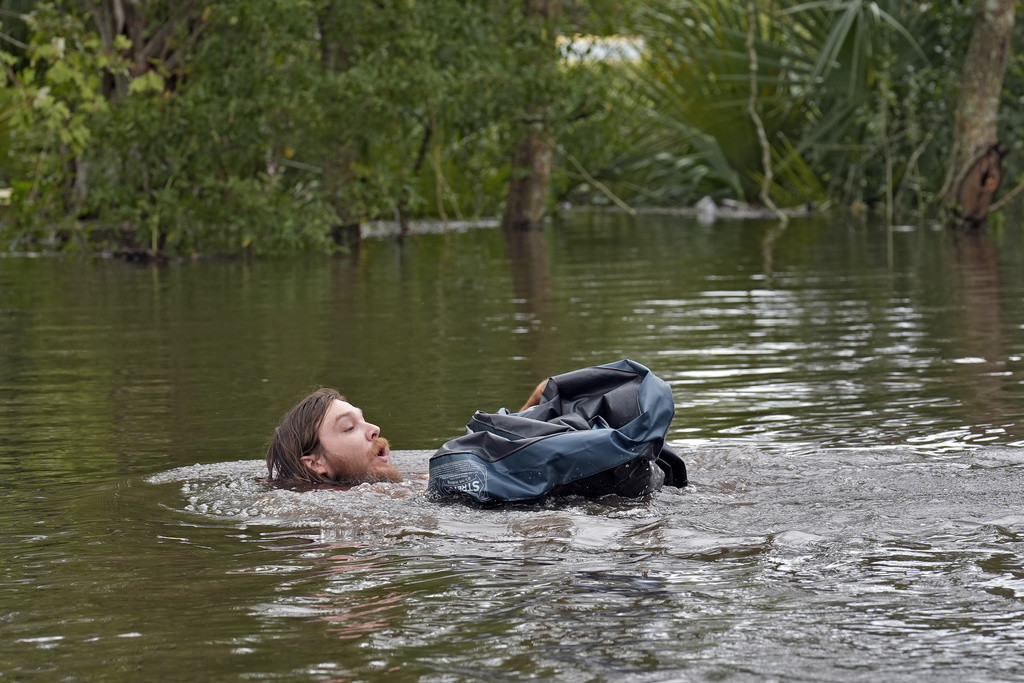 Connor Hughes de Lithia, Florida, se abre paso en una calle inundada junto al río Alafia, el viernes 11 de octubre de 2024, tras el paso del huracán Milton. (AP Foto/Chris O'Meara)