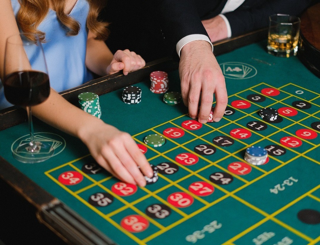 Pareja jugando en un casino a las fichas apostando. Foto: Canva.