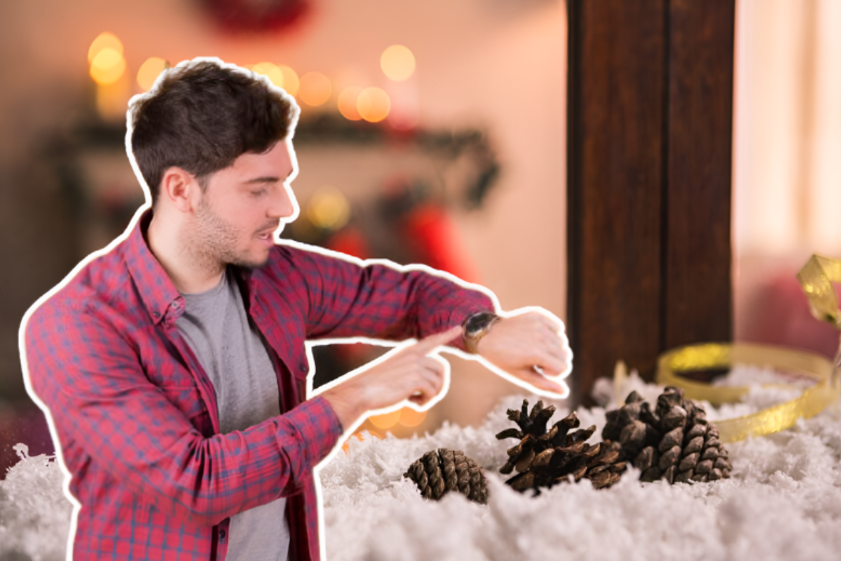 Persona viendo su reloj frente a una chimenea con adornos navideños.     Foto: Freepik, editada en Canva.