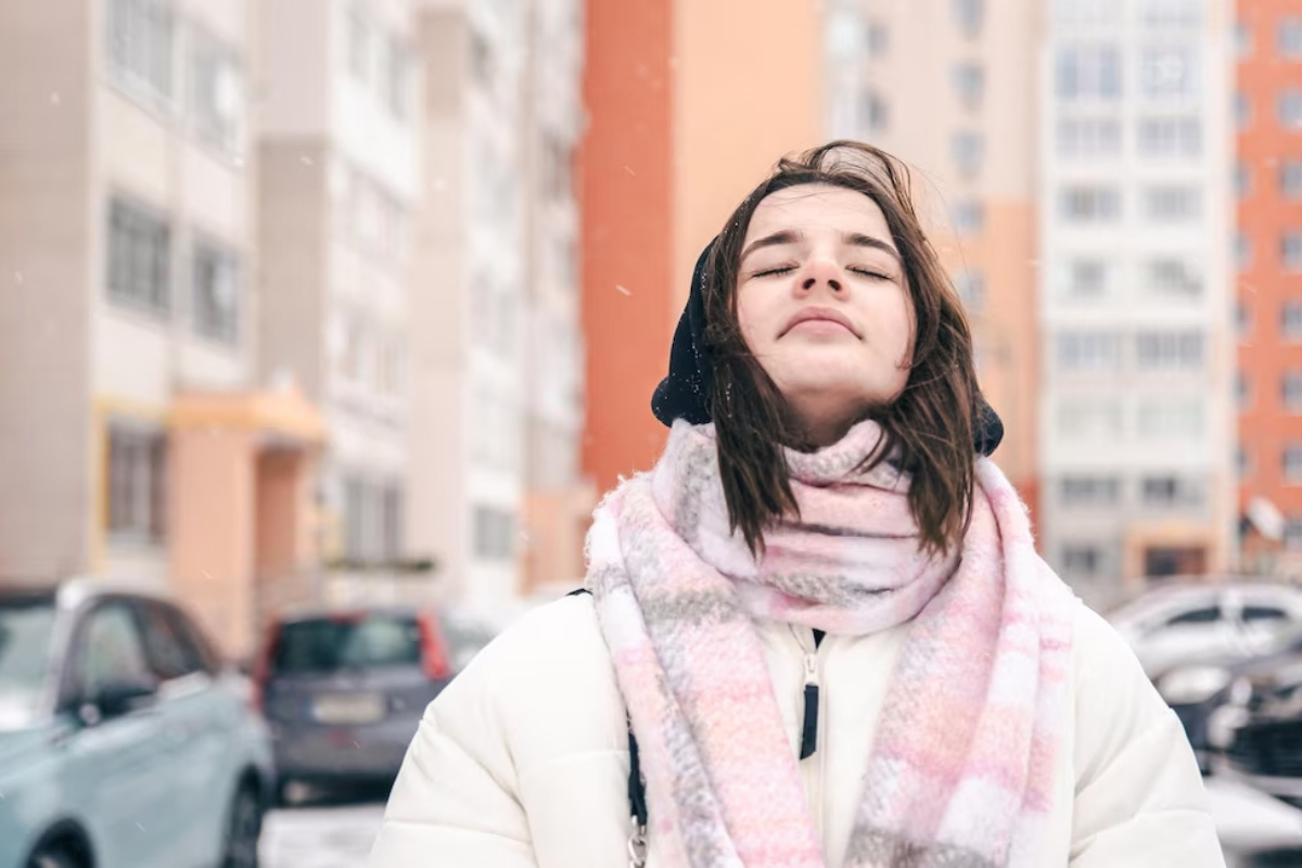 Mujer viendo hacia el cielo con los ojos cerrados.    Foto: Freepik y editada en Canva.