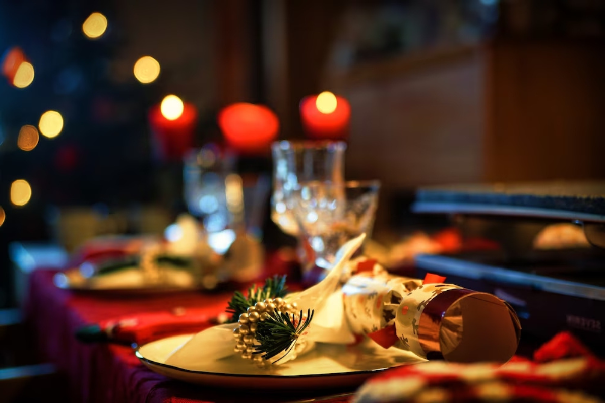 Cena de Navidad con luces rojas de fondo.    Foto: Freepik editada en Canva.