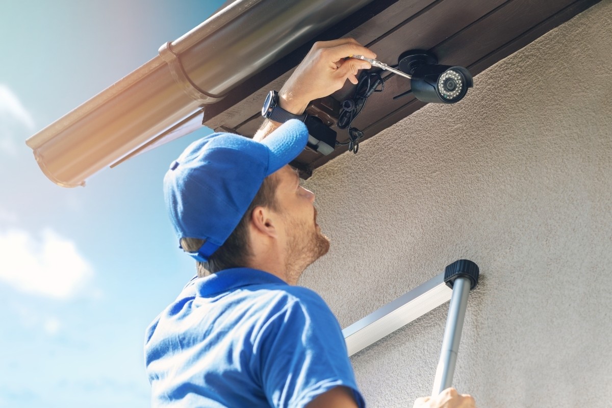 Hombre instalando cámara de seguridad. Foto: Canva