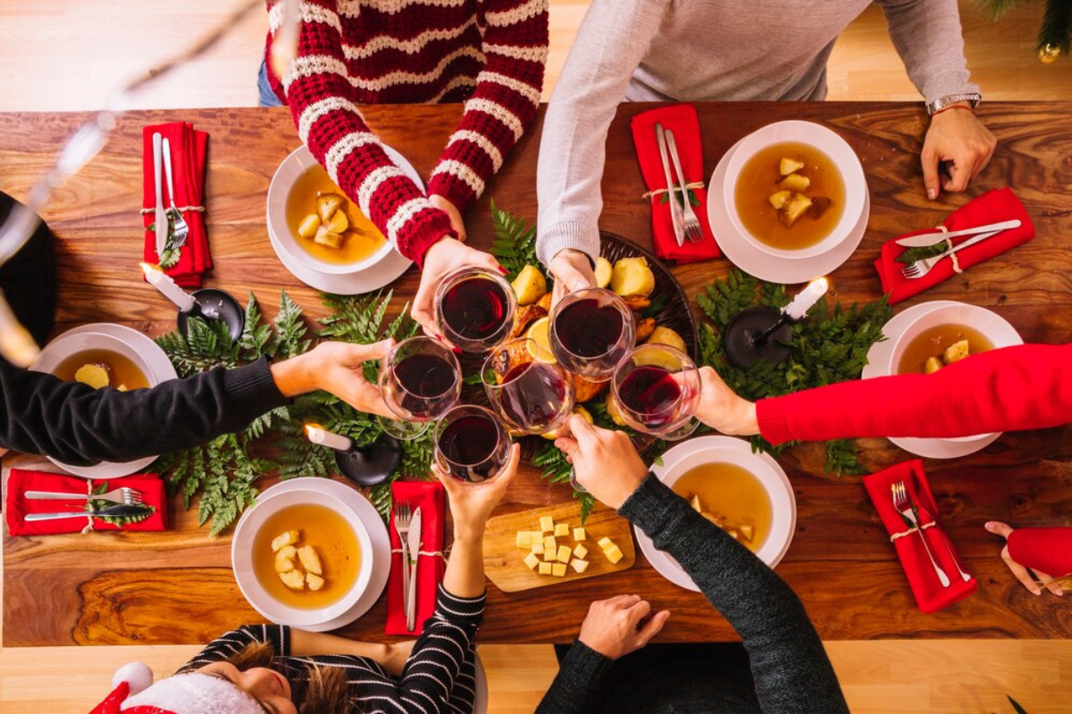 Personas brindando en la Cena de Navidad.   Foto: Freepik, editada en Canva.