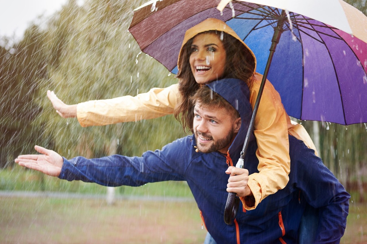 Pareja con impermeables y un paraguas en un día lluvioso. Foto: Freepik