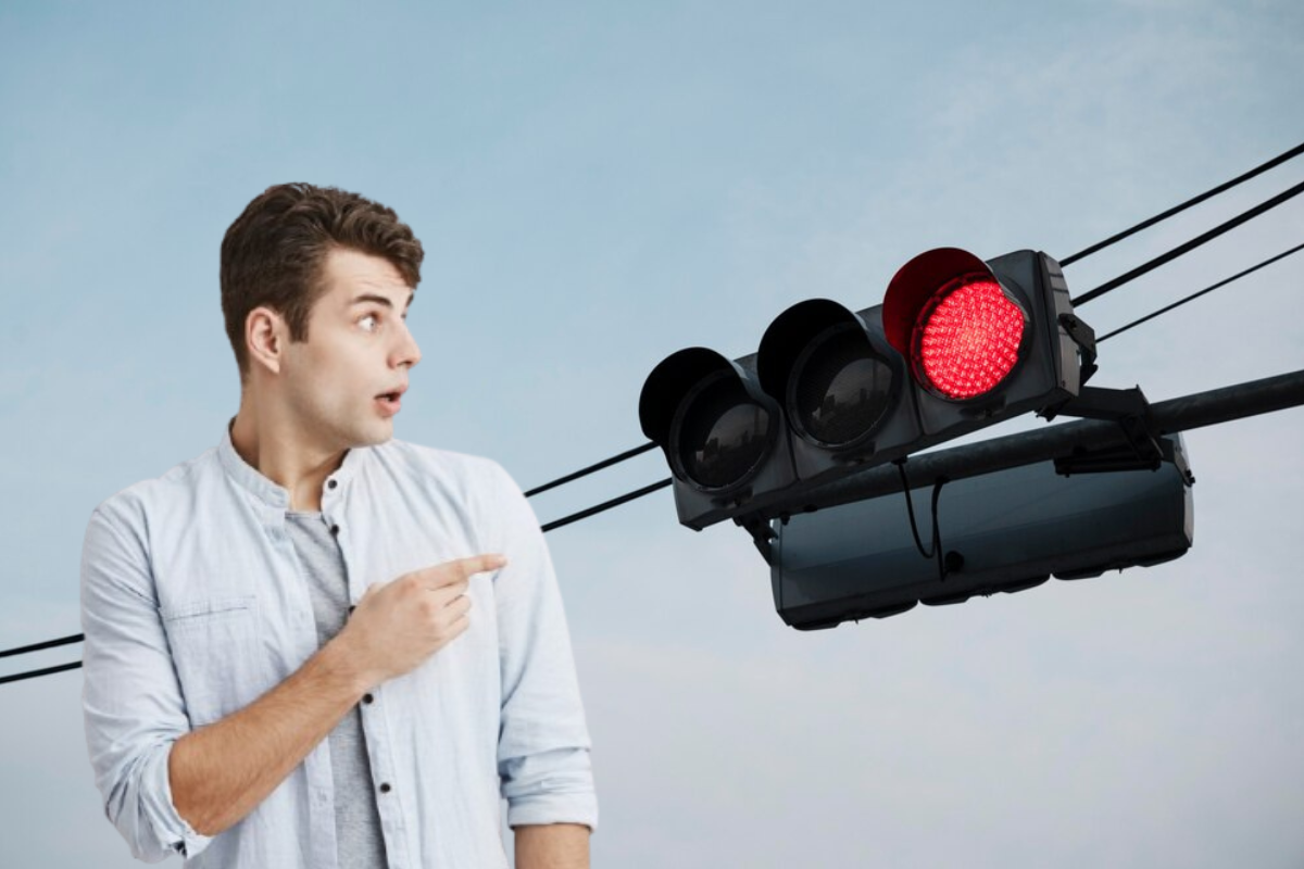 Hombre señalando la luz roja del semáforo.     Foto: Freepik editada en Canva.