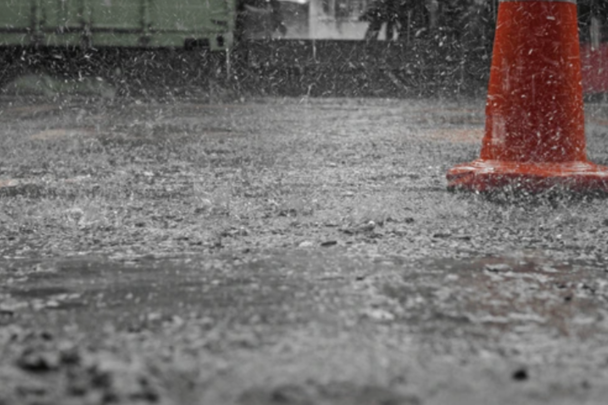 Lluvia fuerte cayendo sobre el asfalto y un cono de seguridad. Foto: Especial