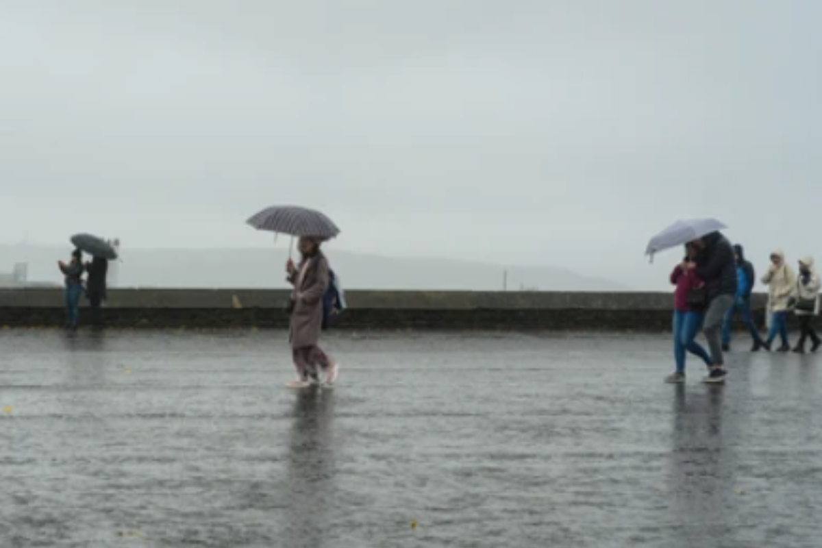 Persona caminando bajo una lluvia fuerte con sus paraguas. Foto: Especial