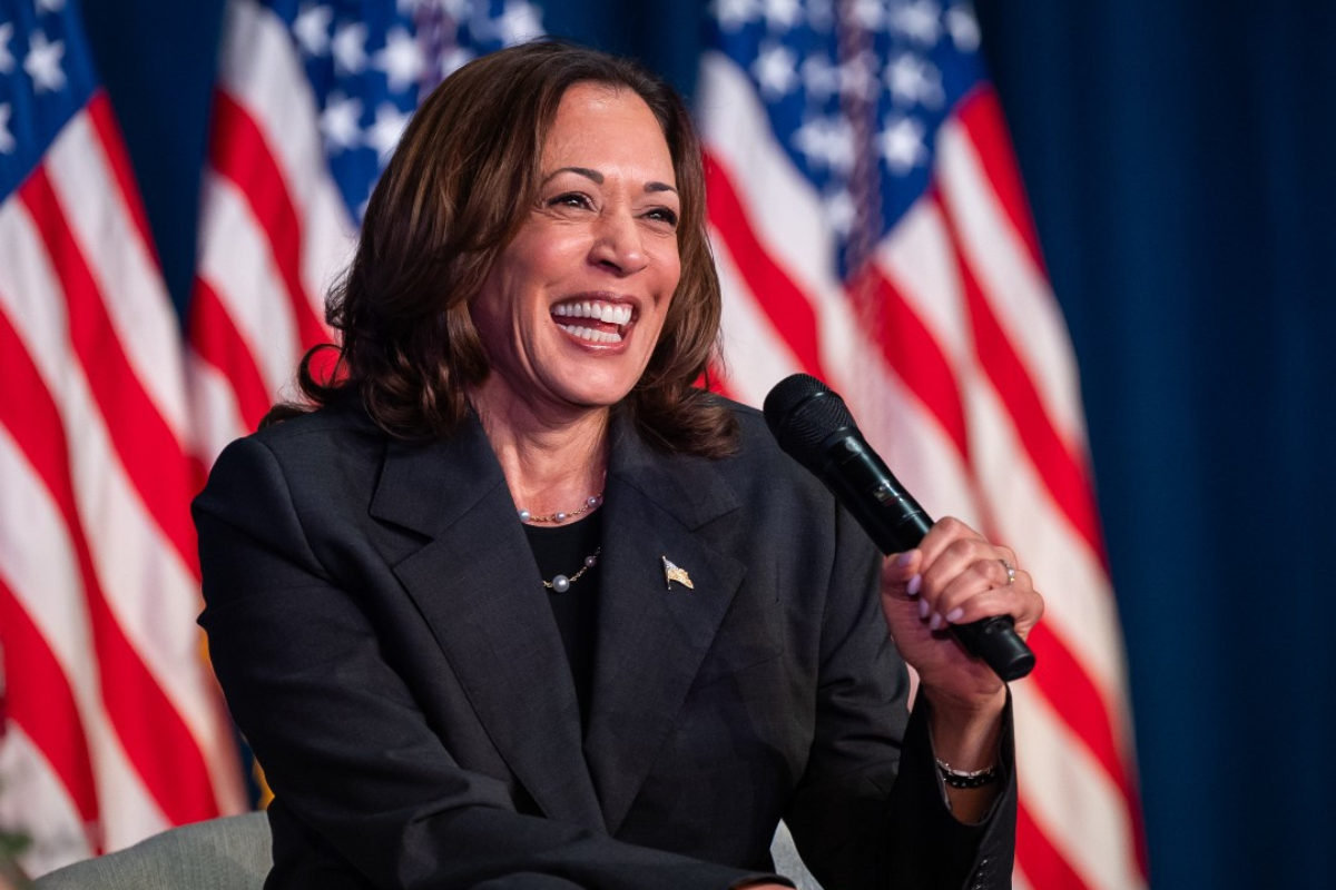 Kamala Harris sosteniendo un micrófono, frente a banderas de Estados Unidos. Foto: X / (@KamalaHarris)